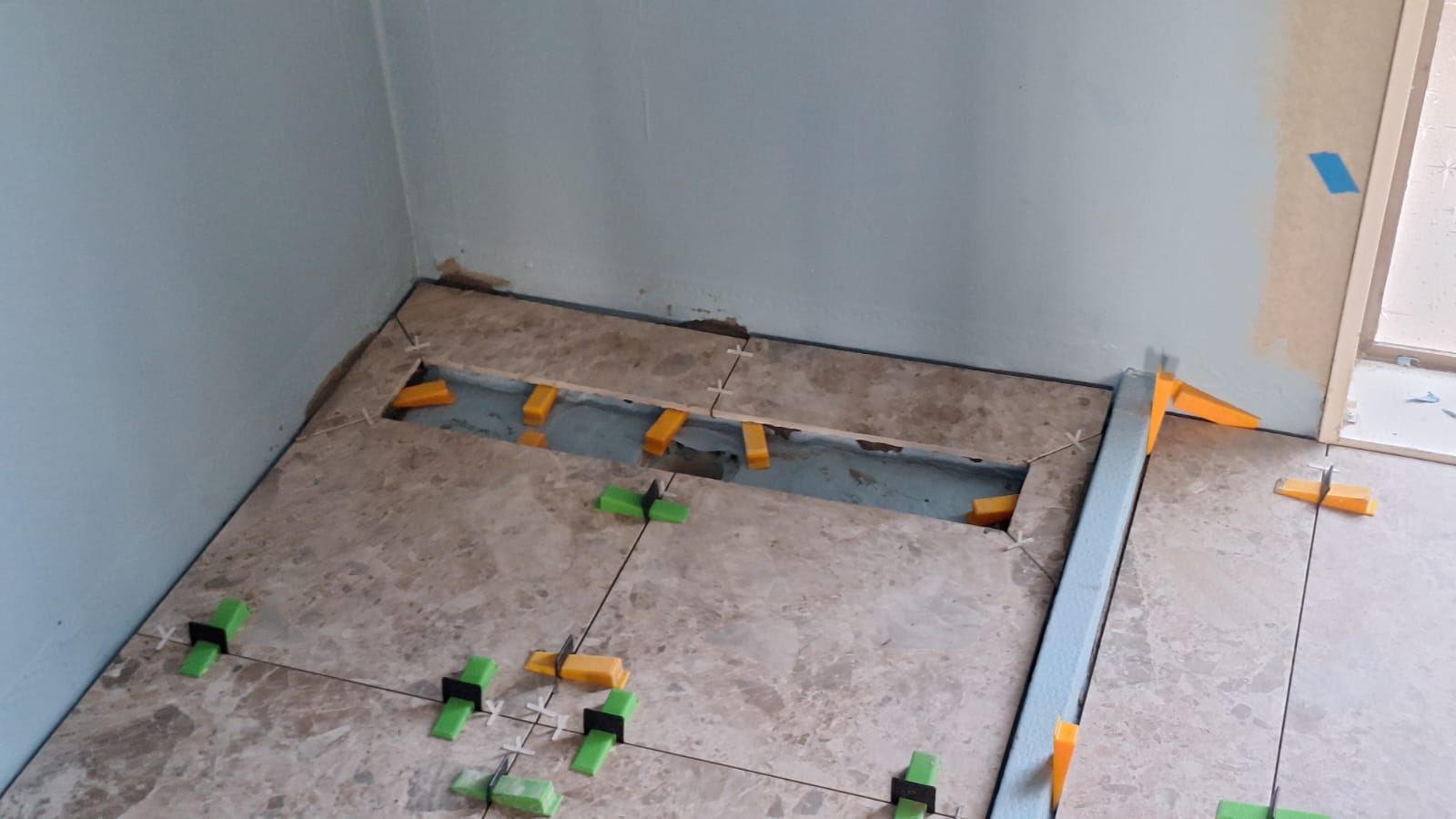 Floor tiles being replaced with levelling clips and spacers during an Auckland tile repair