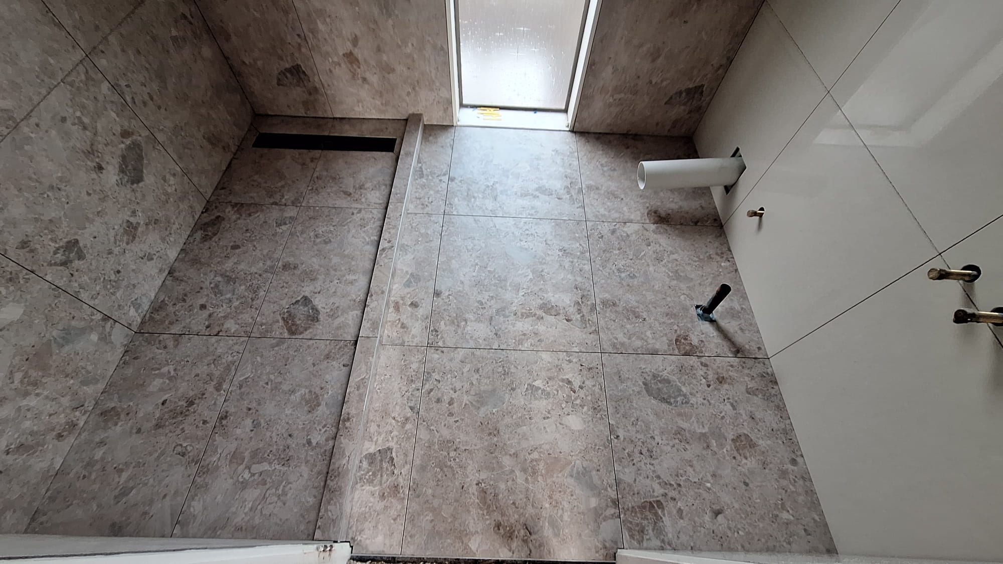 Tiled shower area with linear drain and stone-look floor tiles in an Auckland bathroom