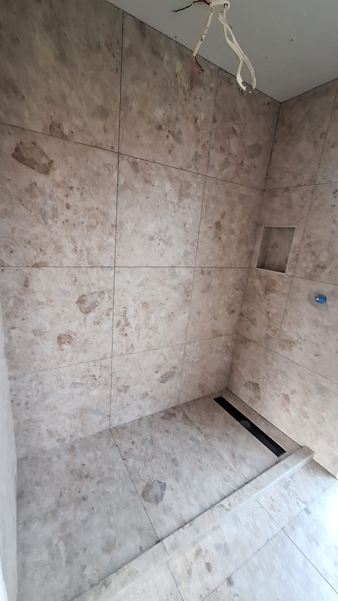 Stone-look wall and floor tiling in an Auckland shower with niche and linear drain