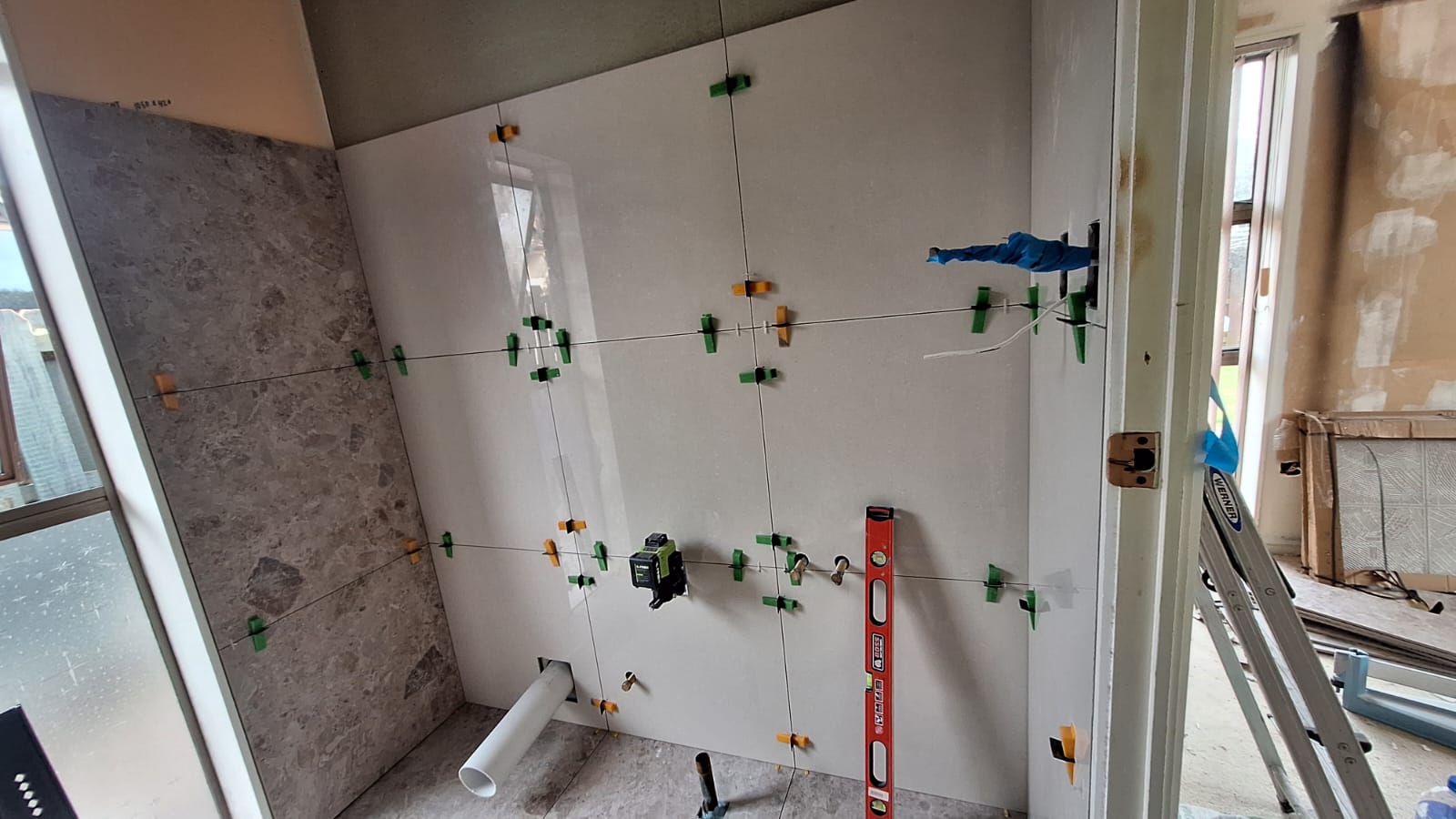 TradePlus tiler setting large-format wall tiles with spacers, clips and a level